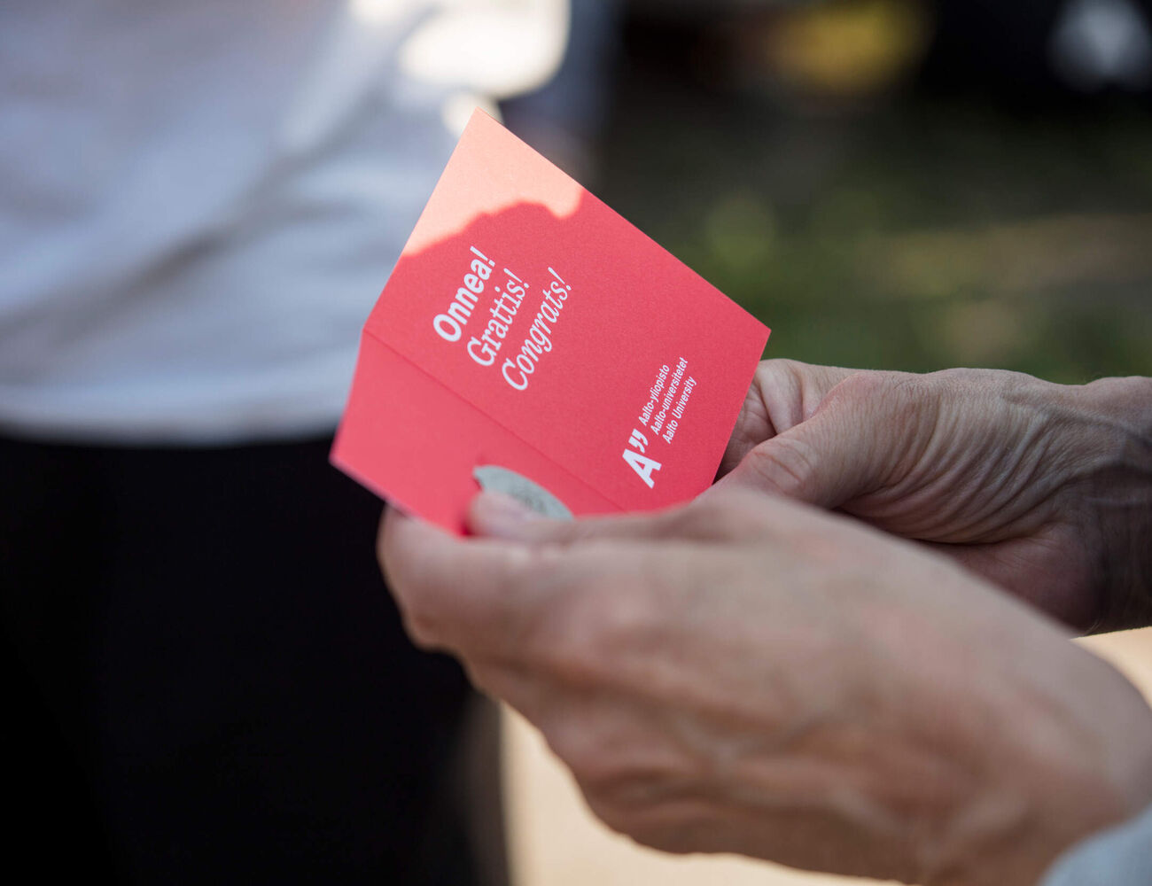 A red greeting card with 'Congrats' written on it for the new alumni of Aalto University. 