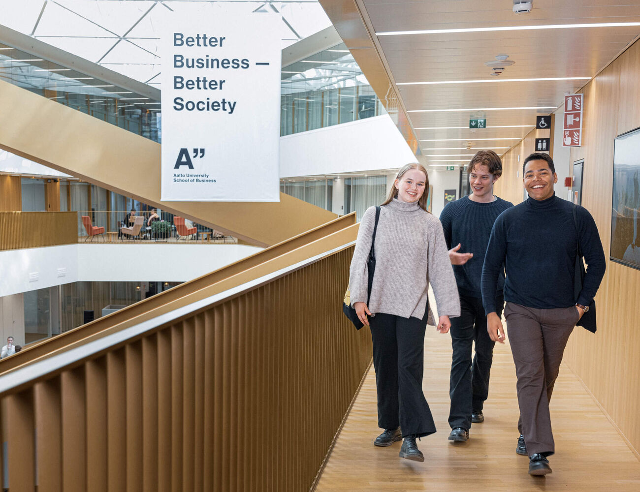 Three students walking in the school corridor side by side and talking