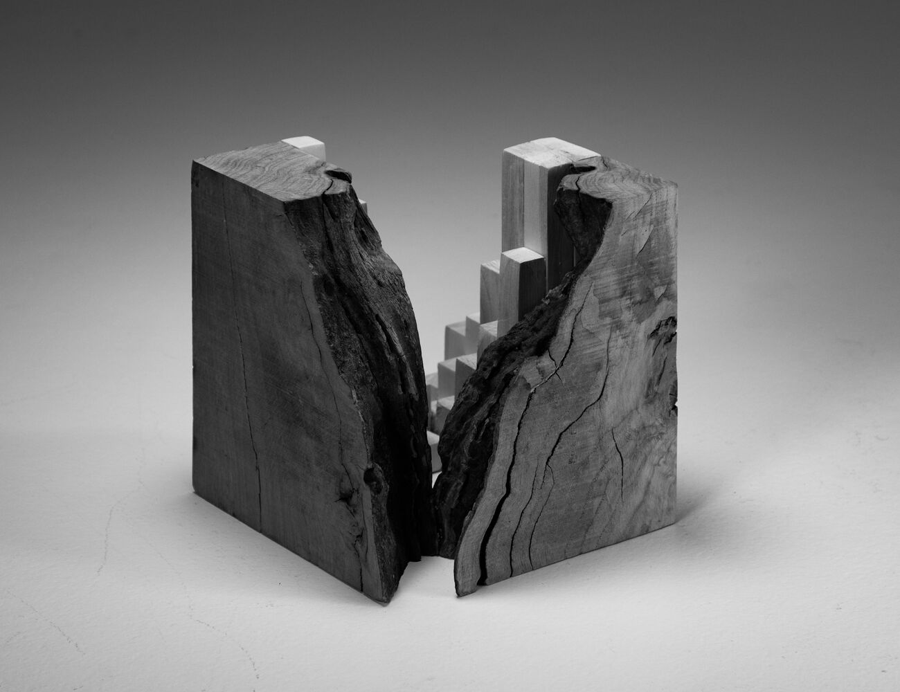 wood cube one half of which is rough edge wood, the other is more abstract consisting of square wood sections