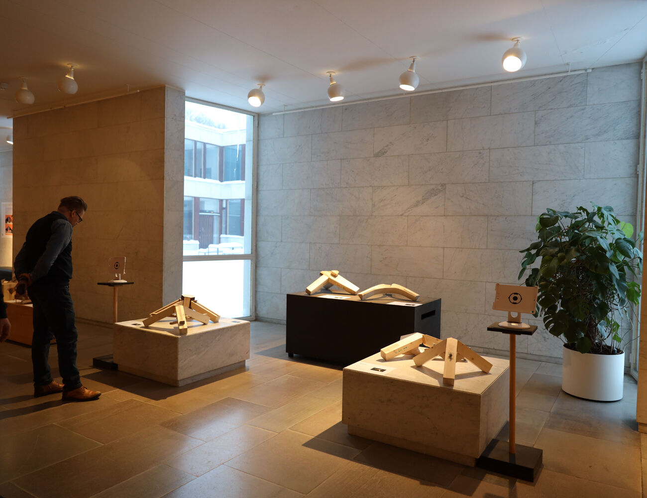 Wooden joint tripods standing on marble plinths in the exhibition space