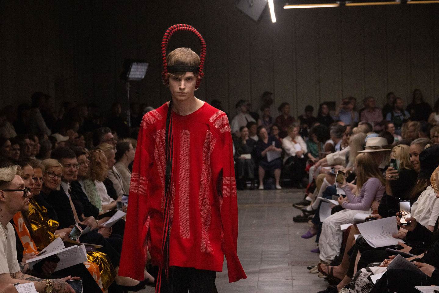 Model walks the catwalk in red outfit and red headpiece