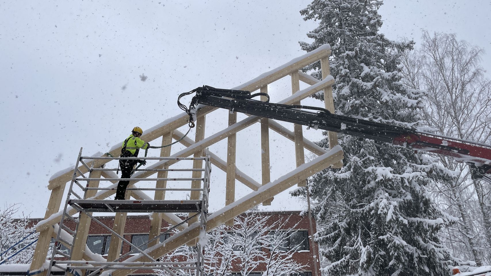Student standing on scaffolding attaching straps to crane hook