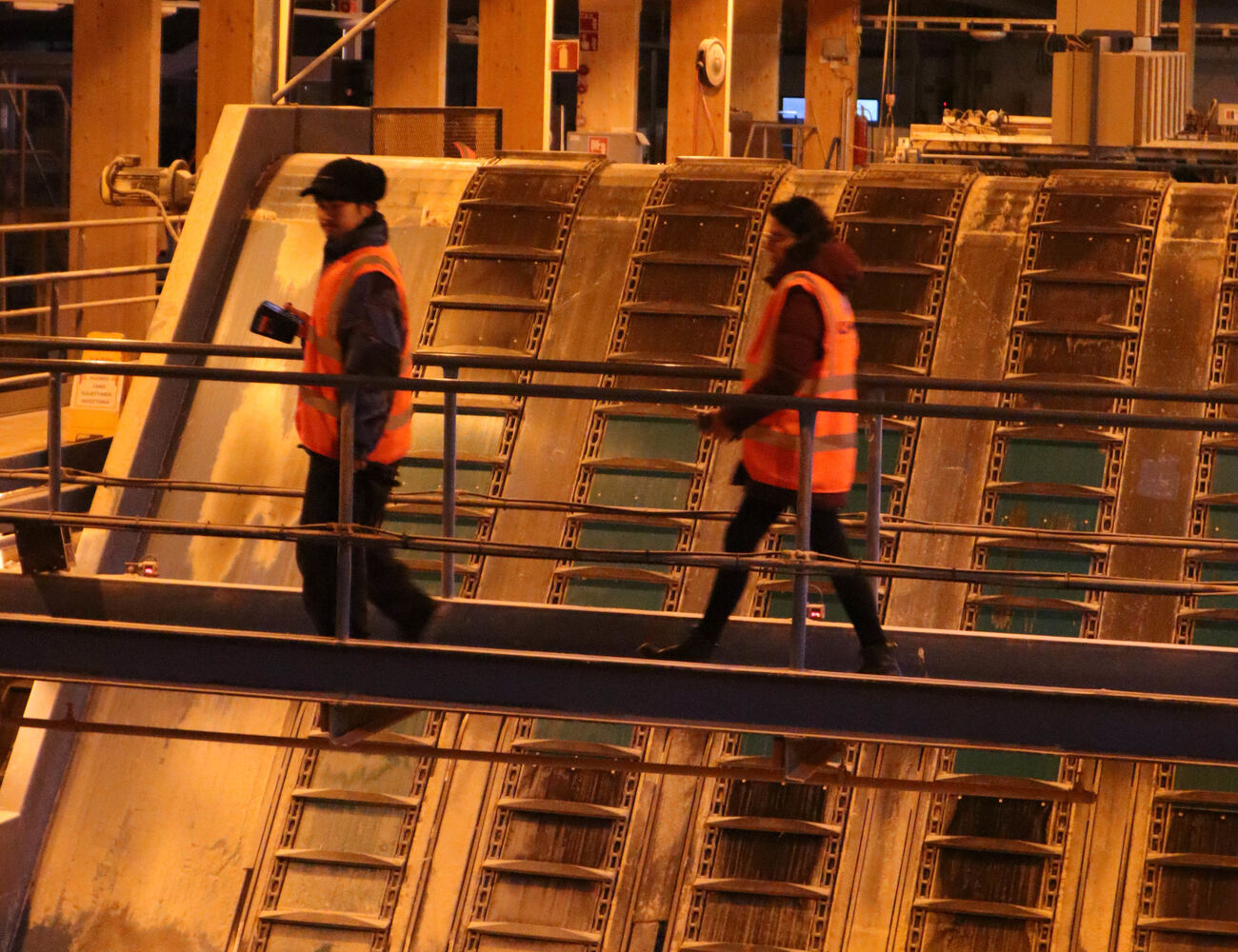 Students walking across a metal bridge over sawmill equipment