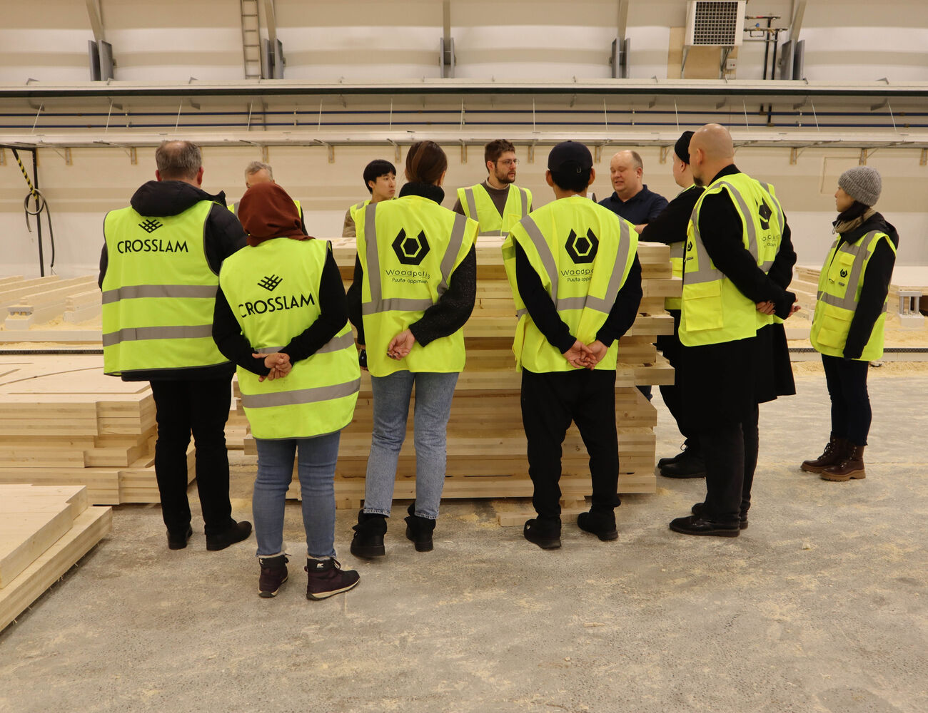 Students standing around a pile of CLT in the Crosslam factory hall