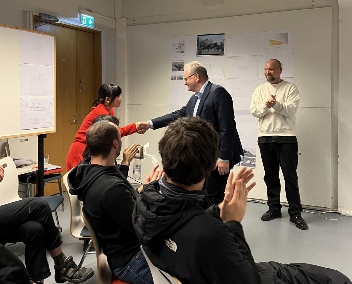 A student is given a handshake by a city representative while other students applaud