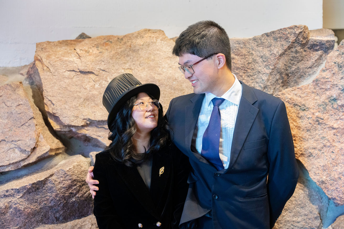 A woman and a man looking at each other, the woman wearing a doctoral hat
