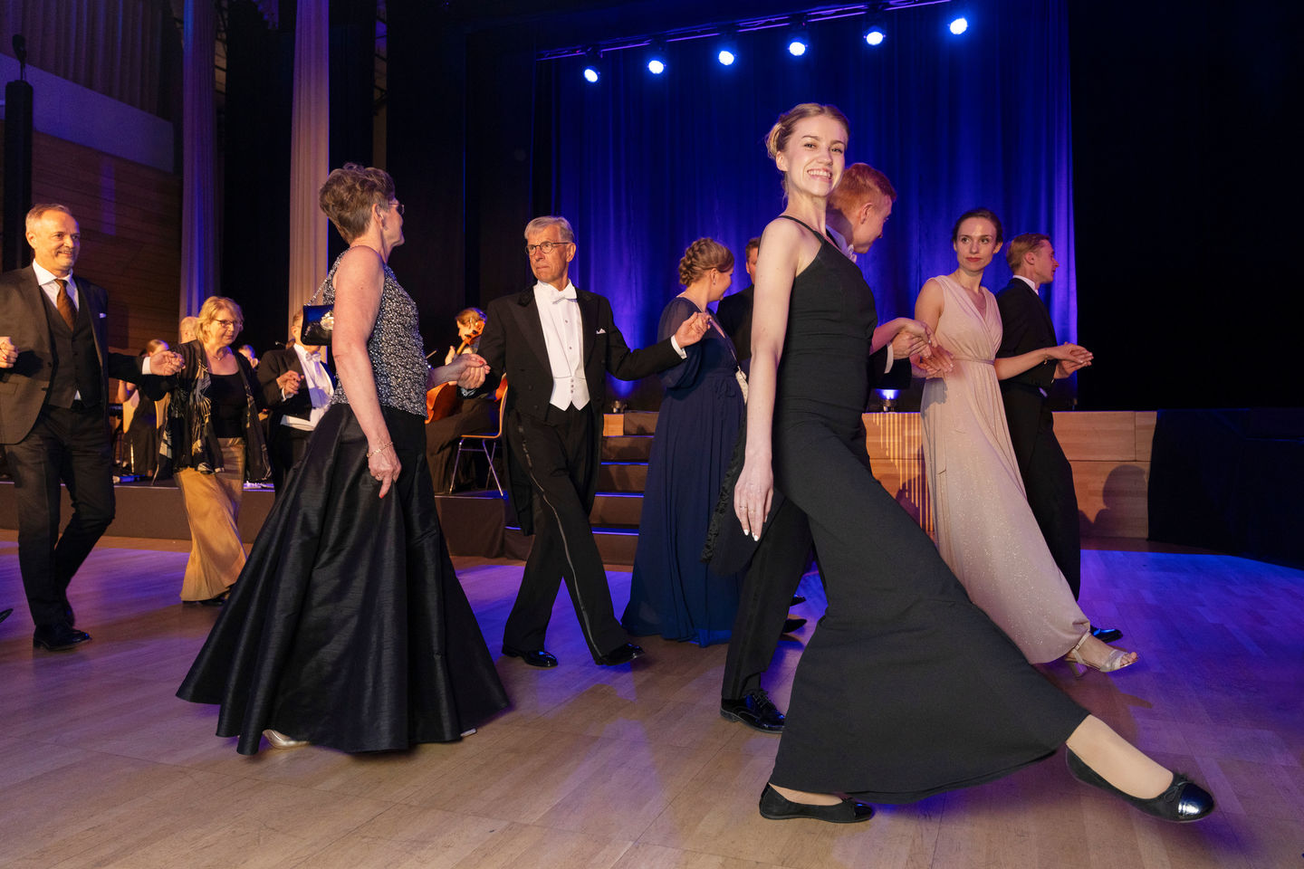 People in evening gowns dancing in a row