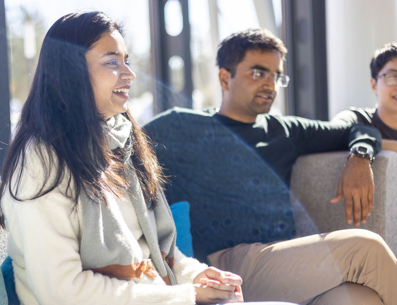 Three students participating in the Aalto International Talent Program sitting on a sofa while visiting their mentor company.