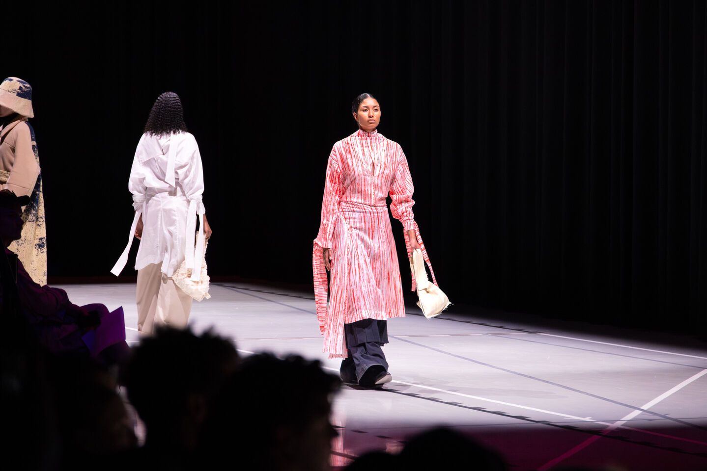 Kolme mallia catwalkilla, yksi punavalkoisessa mekossa, toinen valkoisessa ja kolmas beigessä ja mustassa asussa.