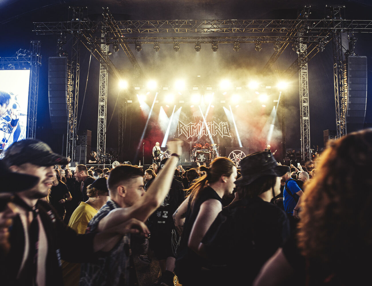 A lively heavy metal concert scene with a band performing under bright lights and a crowd enjoying the music.