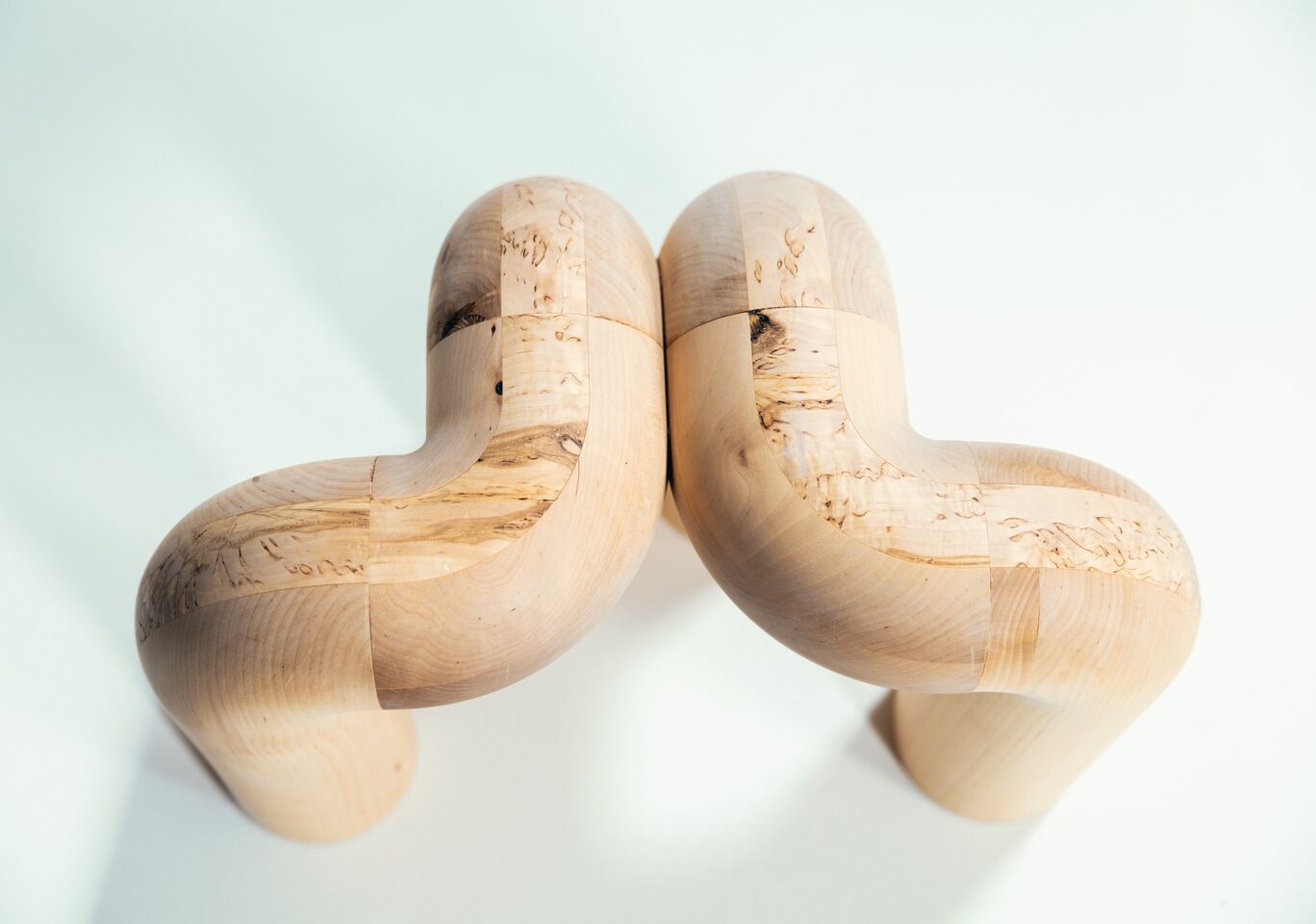 Two wooden sculptures with curved shapes placed close to each other on a light background