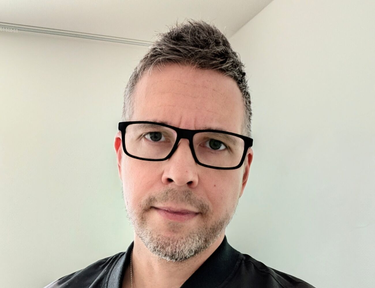 Henkilö, jolla on musta takki harmaan T-paidan päällä ja hopeinen kaulakoru.