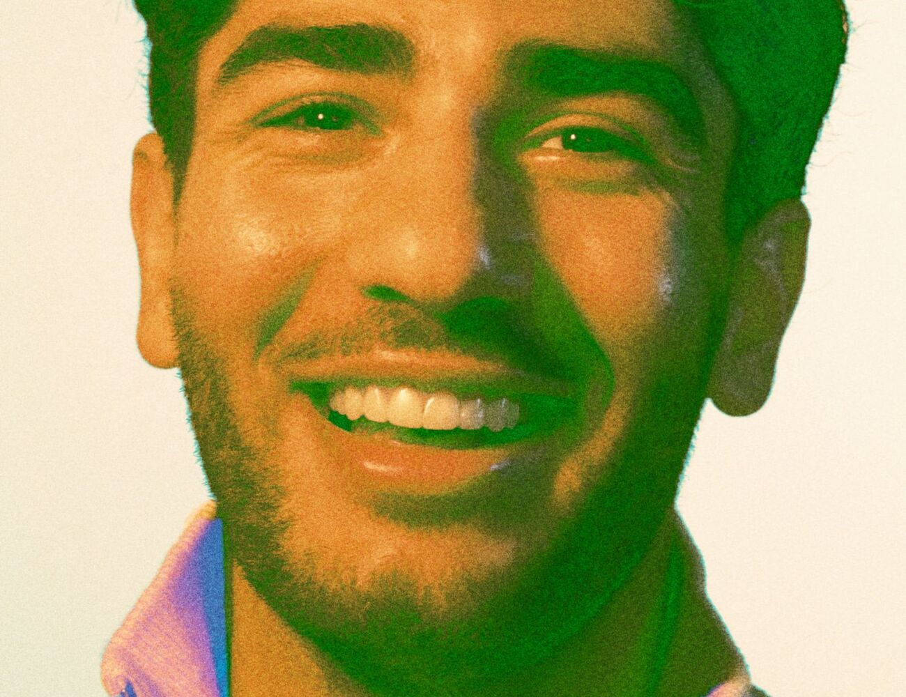 A person wearing a light-coloured zip-up jumper. The background is plain.