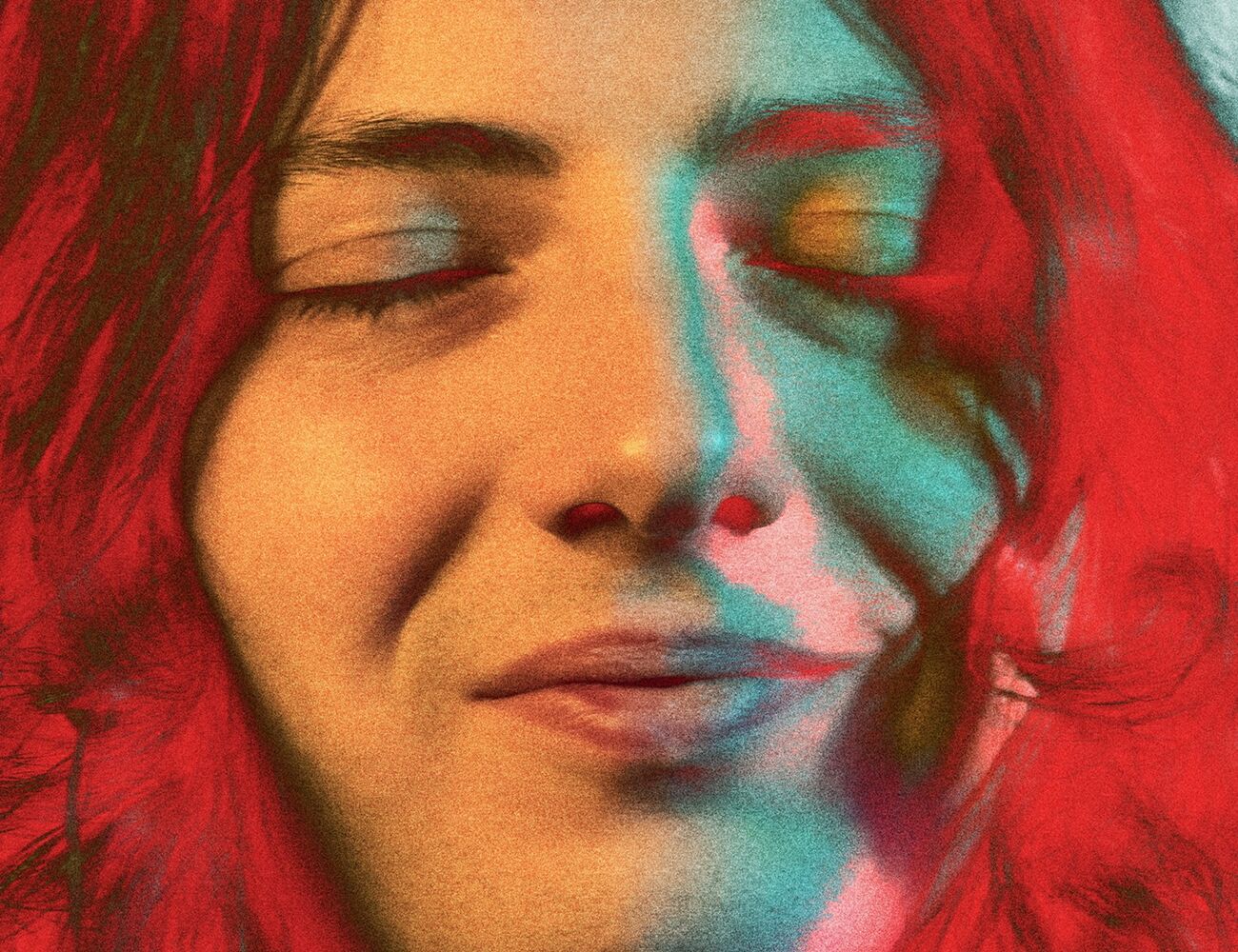 A person with long, wavy red hair against a light blue background.