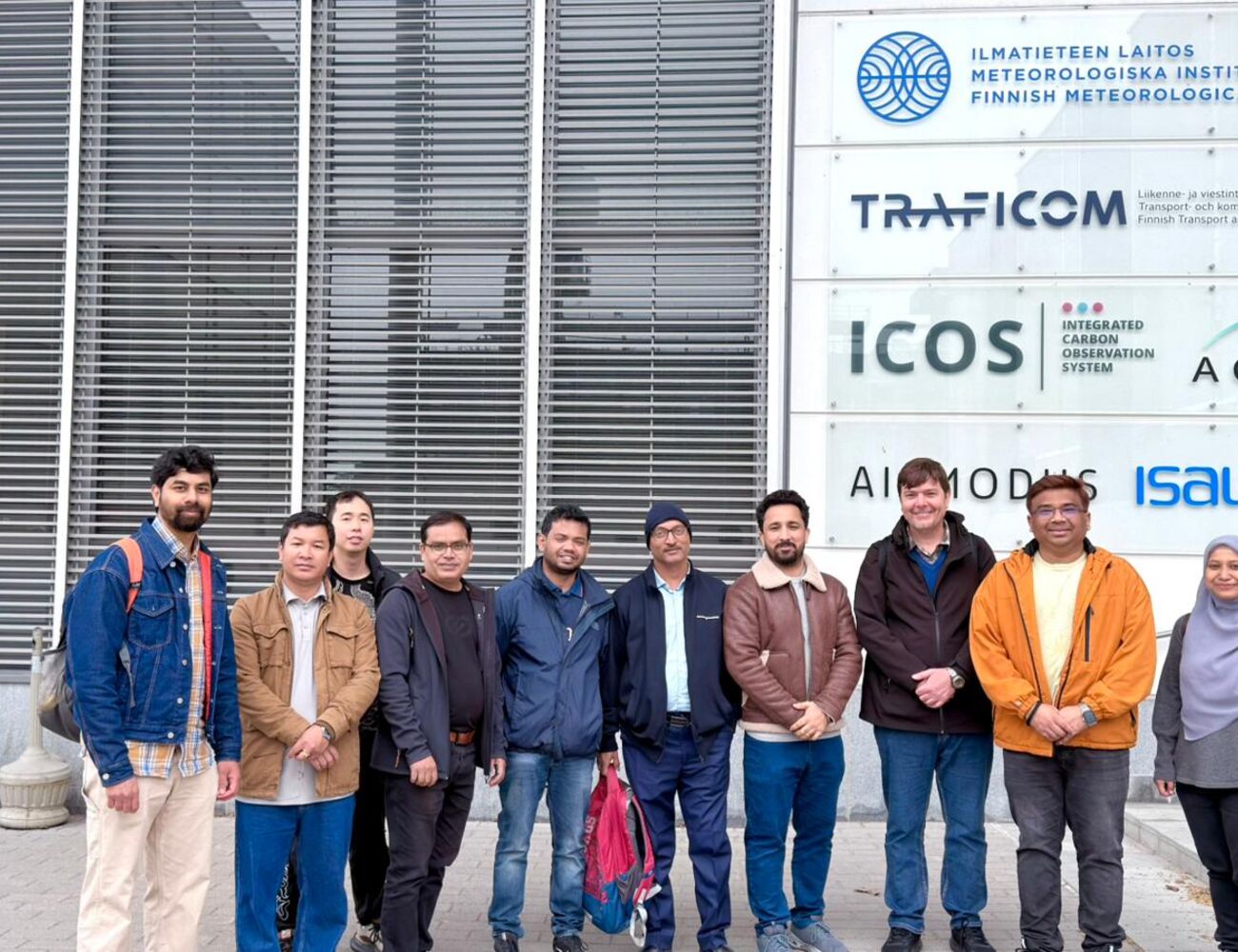 Group of people in jackets standing outside Finnish Meteorological Institute building with logo signs
