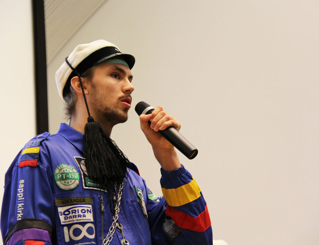 An image of Rudolf speaking into a microphone