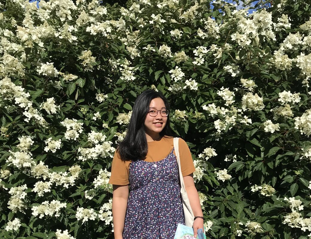 Linh standing in front of a flower wall smiling