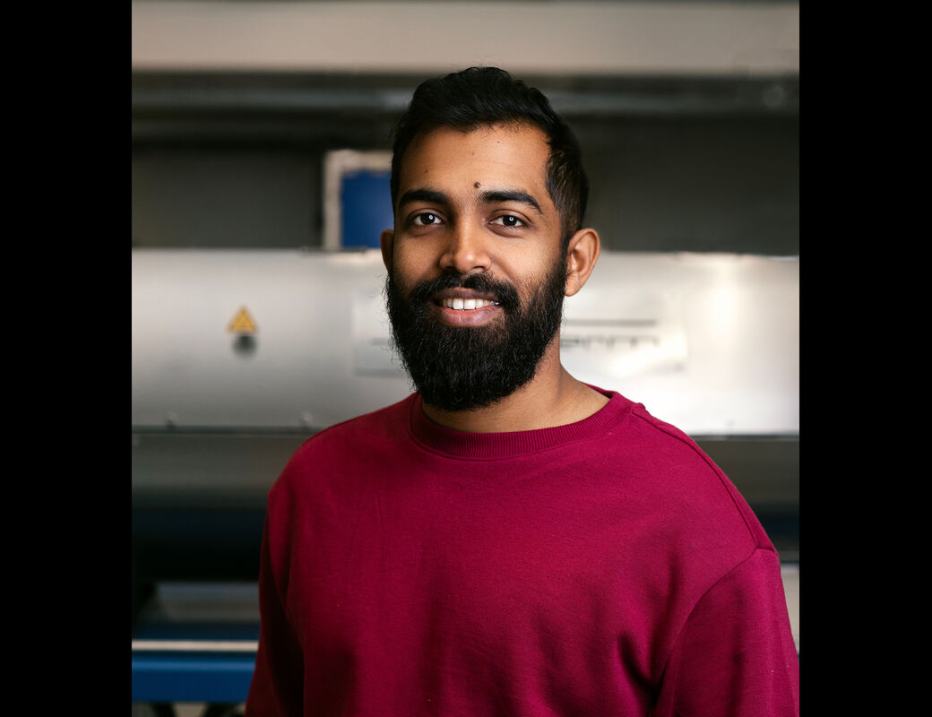 A portrait of Madhawa Basnayaka wearing a red sweater.
