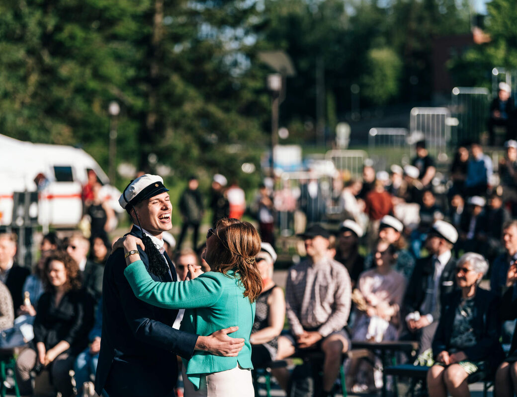 A couple dancing and laughing, rows of graduates on the background