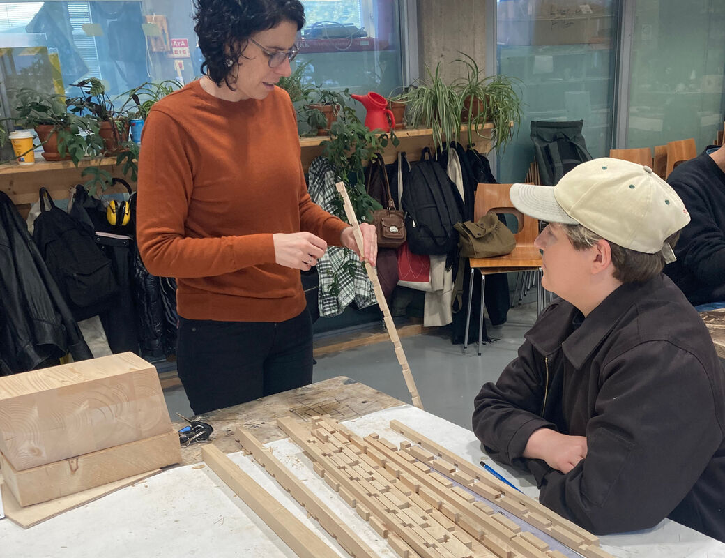 Student and teacher discussing around a pile of square wood dowels