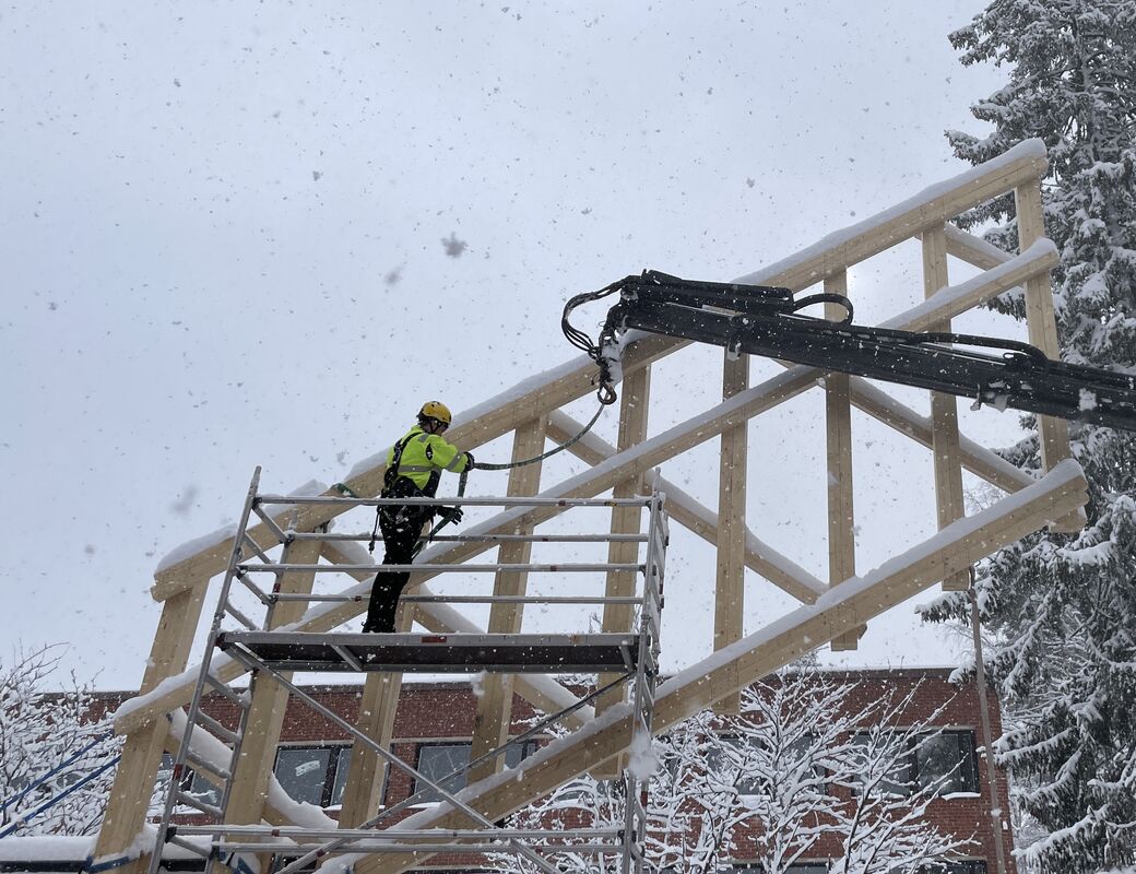 Student standing on scaffolding attaching straps to crane hook