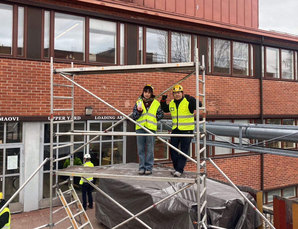 Students watching while standing on scaffolding