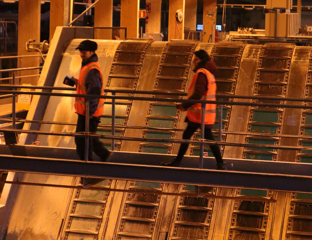 Students walking across a metal bridge over sawmill equipment
