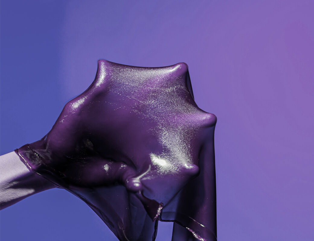 Violetinsävyinen kuva, jossa käsi pitelee venyvää materiaalia
