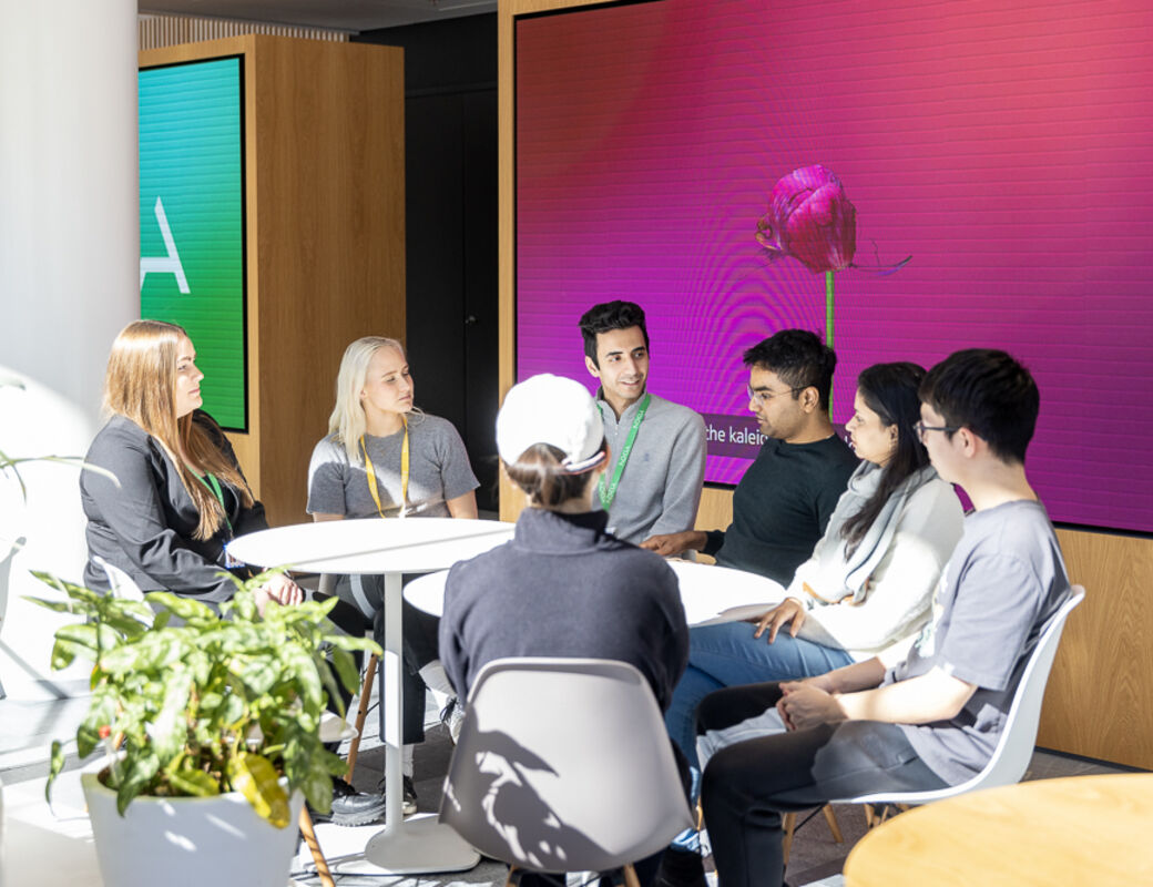 A group of people sitting around a table and talking to each other.