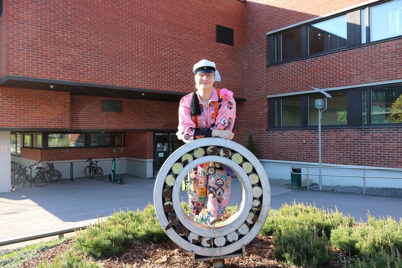 Rasmus Mäkinen poseeraa haalareissa ja ylioppilaslakissa Otaniemen kampuksella.