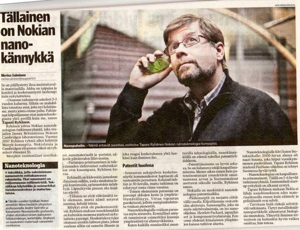Henkilö tummassa takissa pitelee vihreää esinettä korvallaan. Vieressä on artikkeli Nokian nanopuhelimesta.