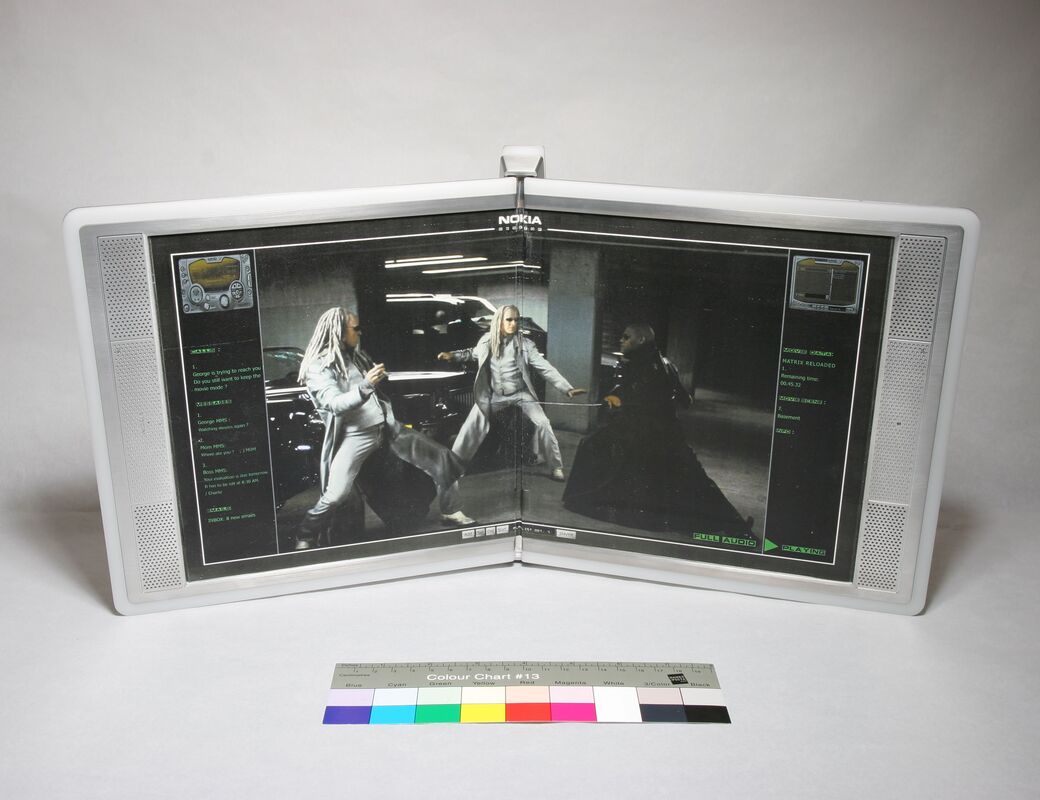 A dual-screen Nokia device displaying a movie scene with two silver-haired characters fighting in a garage.