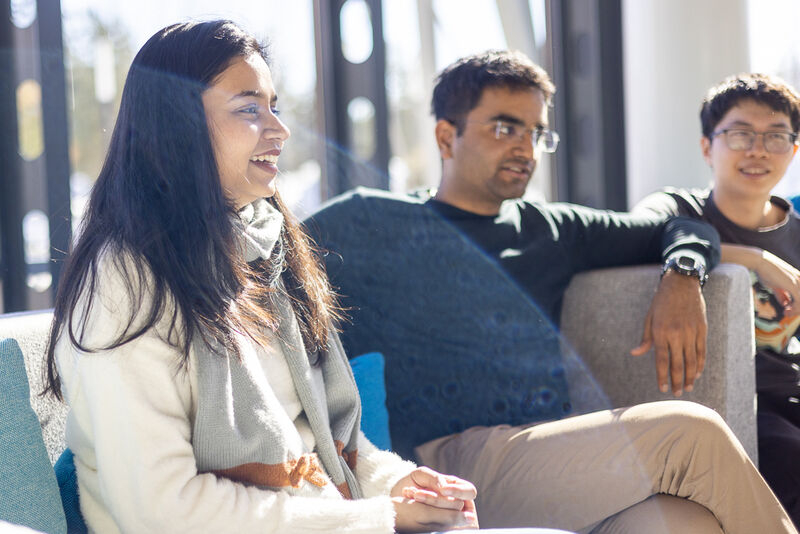 Three students participating in the Aalto International Talent Program sitting on a sofa while visiting their mentor company.