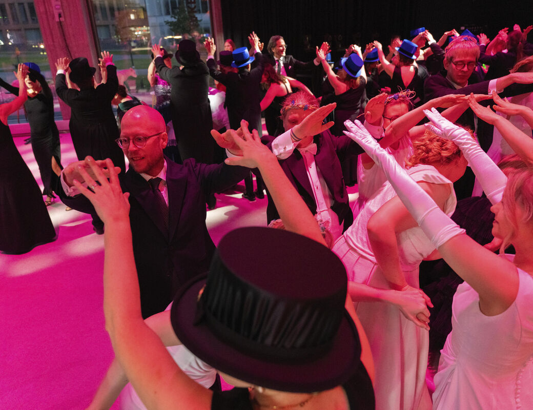 People dancing together, women in white dresses and men in dark suits, with top hats and blue accessories.