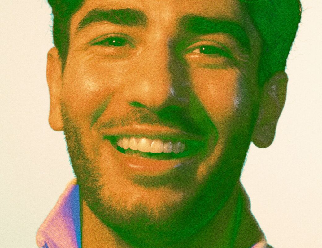 A person wearing a light-coloured zip-up jumper. The background is plain.