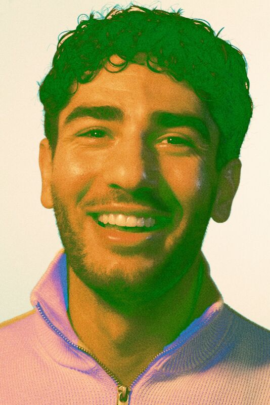 En person som bär en ljus zip-tröja. Bakgrunden är enfärgad.