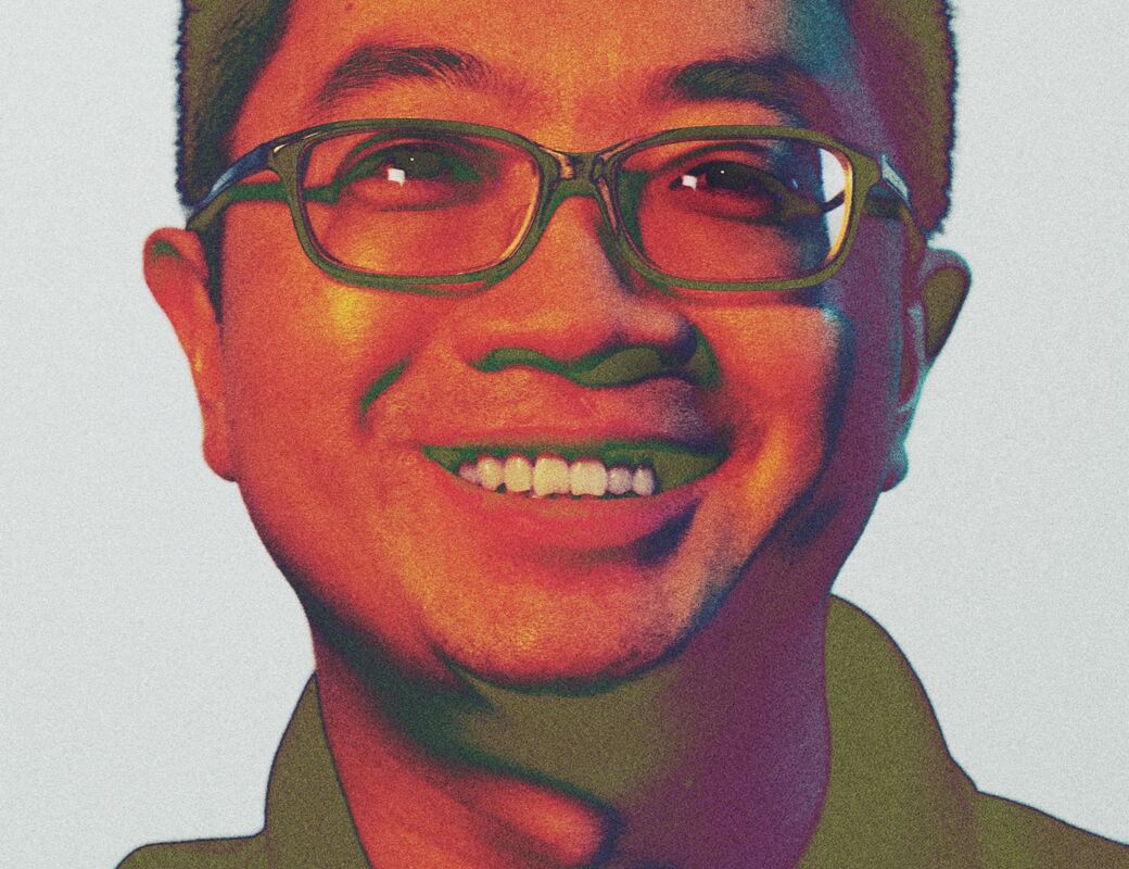 A person wearing a collared shirt with buttons. The background is light grey.