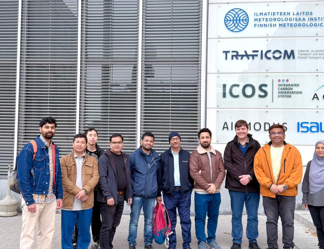 Group of people in jackets standing outside Finnish Meteorological Institute building with logo signs