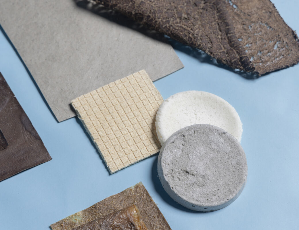 Assorted brown, grey and cream material samples in square and round shapes on a light blue surface.