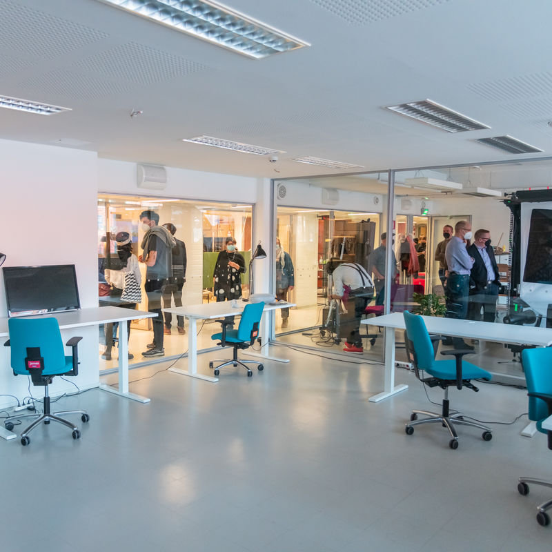 Space 21 corridors full of people, picture taken from the empty room through glass walls.