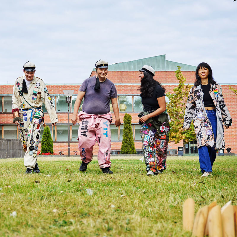 Neljä Aallon opiskelijaa pelaamassa mölkkyä yllään opiskelijahaalarit ja -takit. 
