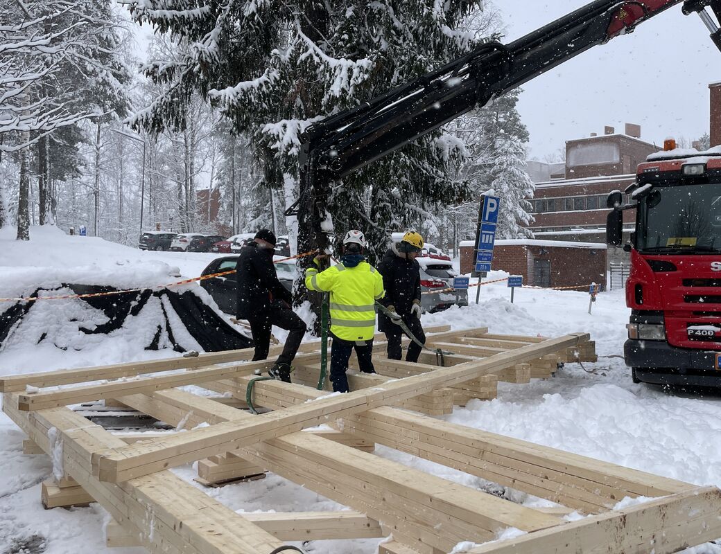 Truss being attached to the crane by students and crane driver