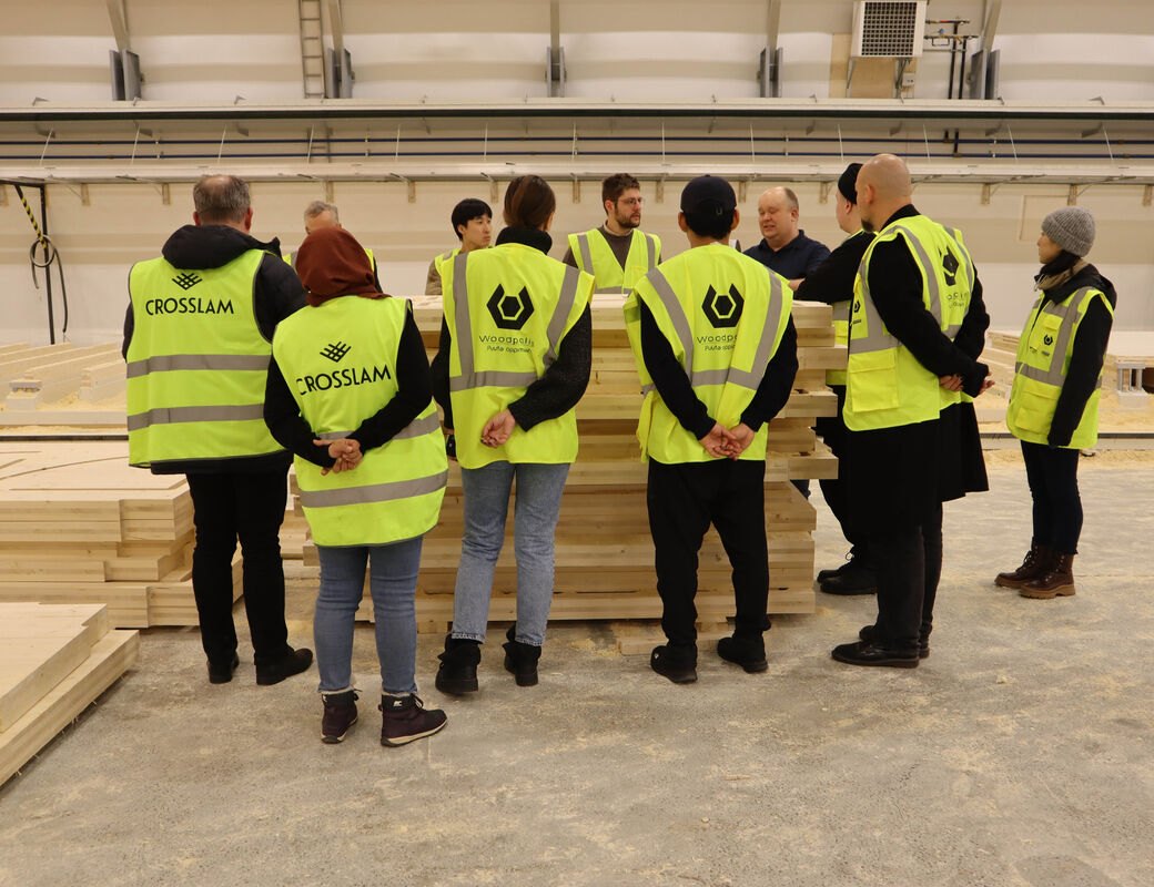 Students standing around a pile of CLT in the Crosslam factory hall