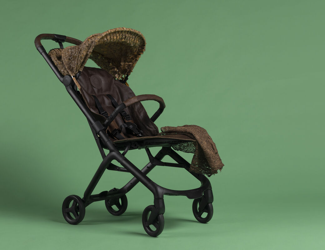 Empty dark brown pushchair with canopy and blanket, on a green studio background