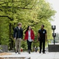 Three students walking on campus on sunny day