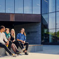 Neljä opiskelijaa istumassa kauppakorkeakoulun edessä.