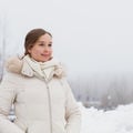 Heli Julkunen seisoo talvisessa maisemassa ja katsoo hymyillen pois kamerasta. Hänellä on päällään valkoinen talvitakki ja taustalla näkyy sumua, puita ja lumihankia.