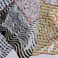 Erilaisia värikkäitä digitaalisesti tulostettuja tekstiilikuoseja lomittain vaalealla tasolla 