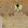 A view through a plywood outdoor art, a person walking in the distance.