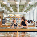 Two women reading together in the Learning Centre library